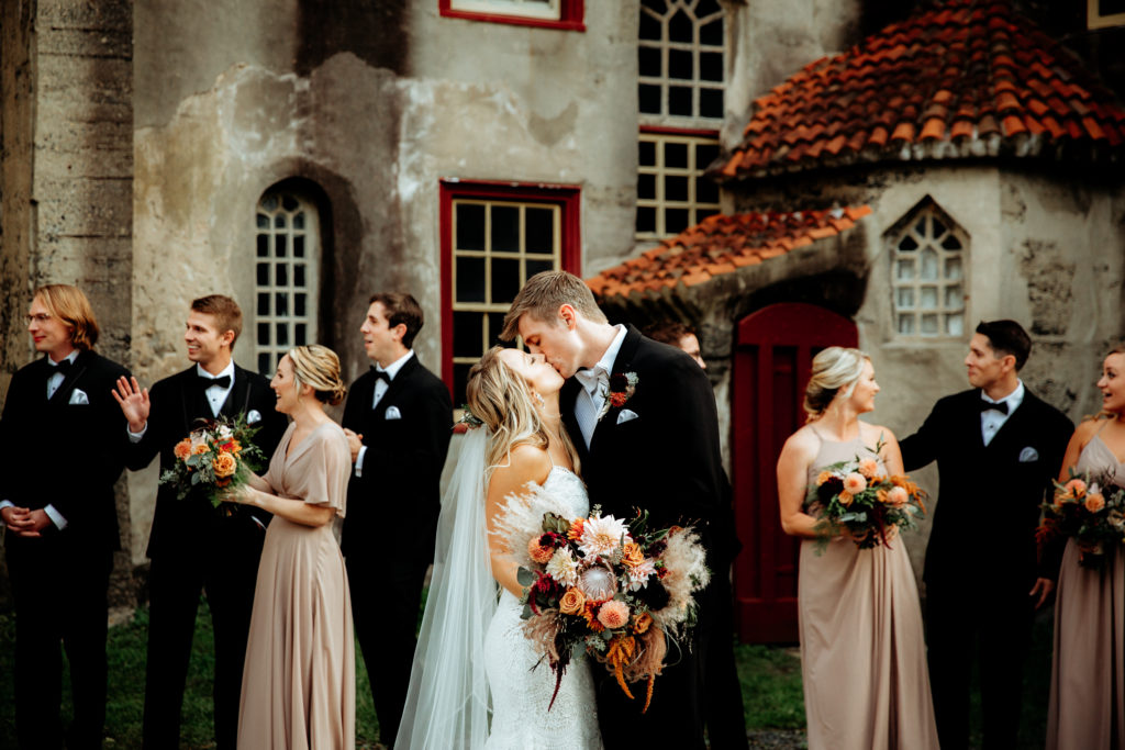 bride and groom kissing at foothill castle wedding with bridal party